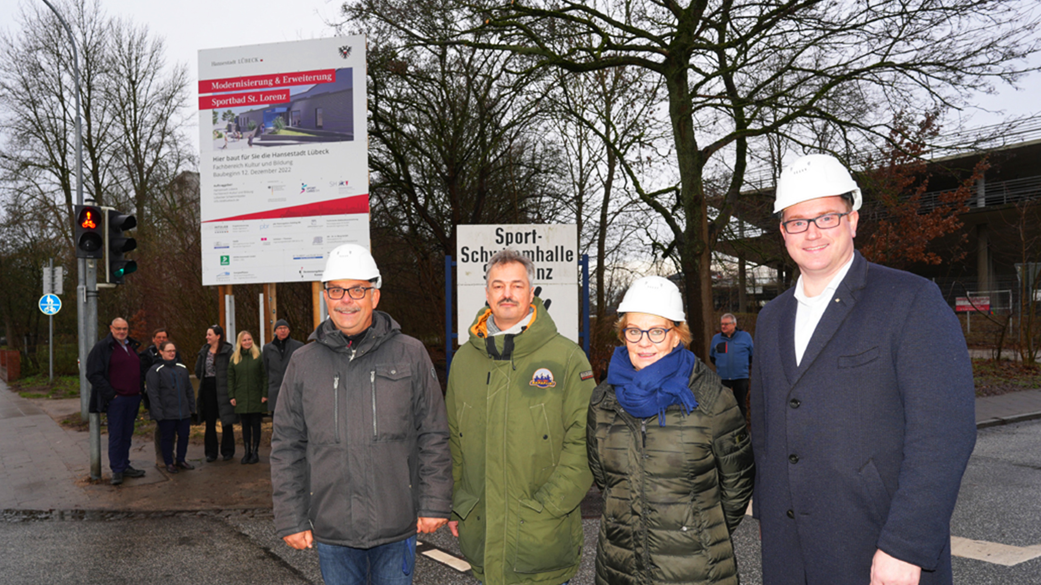Herr Hoppe, Herr Stöver, Senatorin Frank und Bürgermeister Herr Lindenau stehen vor dem Bauschild.